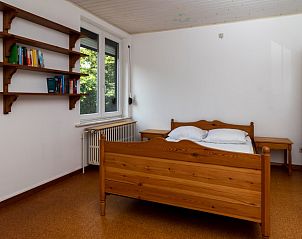 Houten slaapkamerinrichting in Vakantiehuis Salamander, Maasmechelen, Belgi, met boekenplank en raam.