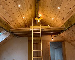Gezellige zolderruimte in Vakantiehuisje in Les Avins-en-Condroz, Ardennen, Belgi. Houten interieur met ladder en sfeervolle verlichting.