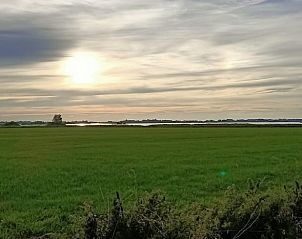 Uitgestrekt landschap met zonsondergang nabij Huisje in Hemelum vakantiehuis in Hemelum, Friesland.