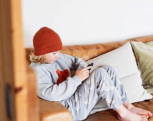 Kind ontspannen op de bank in Vakantiehuis in Hemelum, gezinsvriendelijke sfeer in de Friese meren.