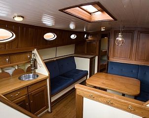 Gezellige binnenruimte van de Bornrif boot in Gaastmeer met comfortabele zitplaatsen en houten interieur.