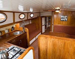 Gezellige binnenruimte van Vrouwezand, vakantieboot in Gaastmeer, met houten interieur en comfortabele zithoek.