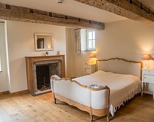 Cozy bedroom in Cottage in Yvoir, located in the Ardennes, Belgium, with wooden beams and fireplace for a rustic atmosphere.
