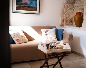 Cozy living room in Holiday Home in Crispiano, Puglia, with comfortable sofa and rustic stone wall.