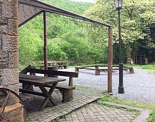 Veranda des Ferienhauses in Purnode in den Ardennen, Belgien, mit Blick auf die grne Natur und rustikale Sitzgelegenheiten.