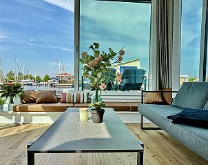 Stijlvolle woonkamer van Vakantiehuis Harboursuite Woudsend, met grote ramen die uitzicht bieden op het Slotermeer en de omgeving.