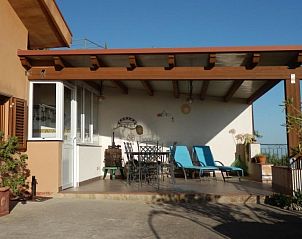 Relax on the sunny terrace of Casa Sirena, a charming vacation home in Cefal, Sicily, with stunning views of the surrounding area.