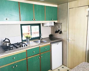 Gezellige keuken in Chalet Toskane aan zee, stacaravan in Viareggio, Toscane, met groene kasten en moderne voorzieningen.