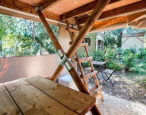 Veranda of Airstay tent house in Cavriglia, Tuscany, with wooden table and view of green surroundings.
