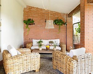 Cozy veranda of Holiday Home in MONSUMMANO TERME, Tuscany, with comfortable rattan furniture and green accents.
