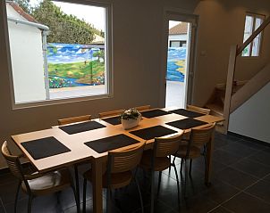 Ruime eetkamer met houten tafel in Vakantiehuis RUST, Middelkerke, Belgische kust, uitzicht op kleurrijke muurschildering.
