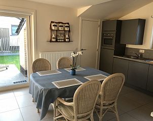 Gezellige eetkamer in vakantiehuis Zee en Polder, Westende, Belgische kust, met moderne keuken en directe toegang tot het terras.