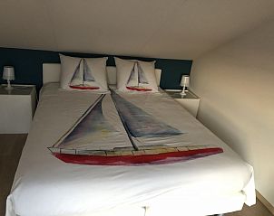 Sfeervolle slaapkamer in vakantiehuis Zee en Polder, Westende, Belgische kust, met zeilbootdecoraties voor een maritieme ambiance.