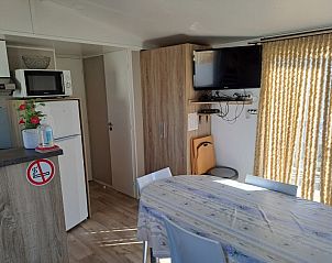 Eetruimte in Vakantieverblijf Wenduine, stacaravan in Wenduine, Belgische kust, met tafel en televisie.