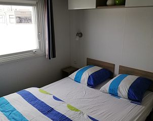 Slaapkamer in Vakantieverblijf Wenduine, stacaravan in Wenduine, Belgische kust, met tweepersoonsbed en raam.