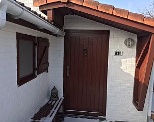 Charmante ingang van Domein Duinendaele vakantiehuis, Adinkerke, met traditionele houten deur en witte gevel.