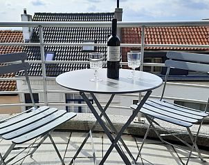 Balkon van Huize Oesjoe in Bredene met zitje en uitzicht op de daken van de Belgische kust.