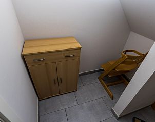 Opbergruimte in Huize Oesjoe, Bredene met houten kast en kinderstoel.