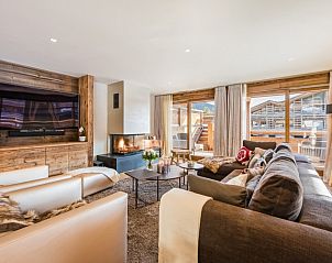 Gezellige woonkamer in Challet Teaga Kitzbuhel, Tirol, met open haard en uitzicht op de bergen.