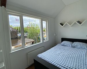 Slaapkamer in Havenhuisje, vakantiehuis in Terherne, met groot raam en uitzicht op het Sneekermeer.