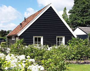Buitenzijde van 't Oppertje vakantiehuis in Terherne, omgeven door bloeiende tuin, nabij Friese meren.