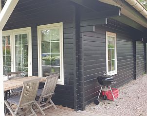 Veranda van vakantiehuis De Koumelker in Terherne, Sneekermeer, met houten tuinmeubilair en barbecue, omgeven door groene natuur.