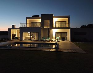 Villa da Figueira in Nadadouro, Portugal, at sunset with illuminated terraces and pool for a luxury vacation home experience.
