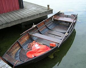 Ontdek Cottage on an Island in Harstena, Gtaland, Zweden met een traditionele houten boot aan de steiger, ideaal voor natuurliefhebbers.