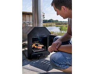 Man stookt houtkachel bij Huisje in Wapserveen, Zuidwest Drenthe.