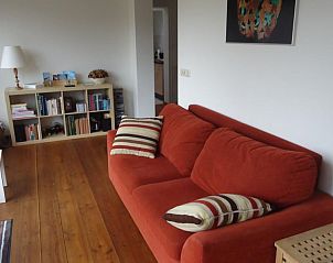 Knusse leeshoek in Landhuisje Leda, een vakantiehuis in Dwingeloo, Zuidwest Drenthe, met een rode bank.