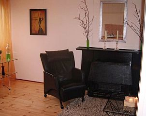 Stijlvolle fauteuil bij open haard in Vakantiehuis in Drachten, Friese sfeer.