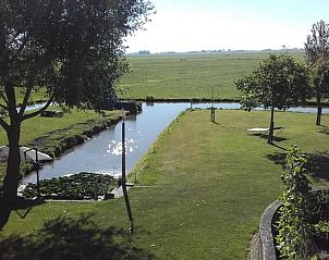 Uitzicht op de tuin en het water bij Huisje in Bolsward, vakantiehuis in Friesland, biedt rust en natuur.