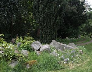 Weelderige tuin met stenen bij Vakantiehuis in Oldeholtpade, Friesland.