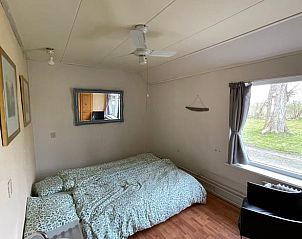 Gezellige slaapkamer van Huisje in De Westereen, vakantiehuis op het Friese platteland, met uitzicht op de groene natuur in Friesland.