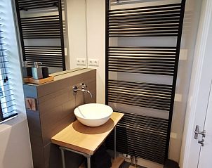 Moderne badkamer in Huisje in Kootstertille, vakantiehuis op het Friese platteland, met stijlvolle wastafel en designradiator.
