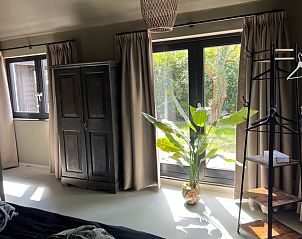 Lichte slaapkamer in vakantiehuis in Spanga met grote ramen en uitzicht op de tuin.