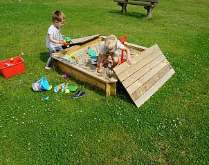 Kinderen spelen in de zandbak bij Huisje in Swichum, perfect voor een gezinsvakantie in Friesland.