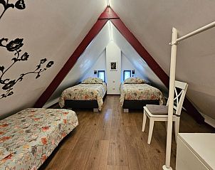 Slaapkamer op zolder in Huisje in Jistrum met drie eenpersoonsbedden en houten vloer.