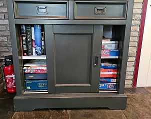 Boekenkast in vakantiehuis Jistrum met spellen en boeken voor ontspanning.