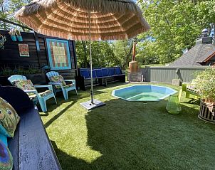 Buitenterras met zwembad bij Vakantiehuisje in Boksum, Friesland, omgeven door groen en uitgerust met ligstoelen.