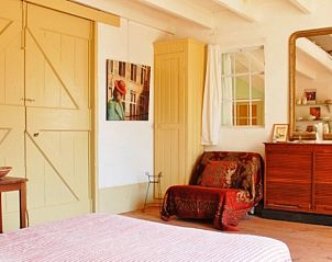 Sfeervolle slaapkamer bij Kunsthof de Heuf, een bed and breakfast in Buren, Gelderland, met een warme en uitnodigende binnenruimte.