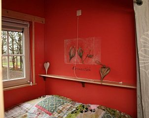 Sfeervolle slaapkamer met rode muur in Kom in de Bedstee Winterswijk, vakantiehuis in Winterswijk, Achterhoek, Gelderland.