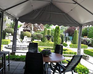 Gezellig zitgedeelte op het terras van Welgelegen 2 chalet in Voorthuizen, Veluwe met uitzicht op groene tuin.