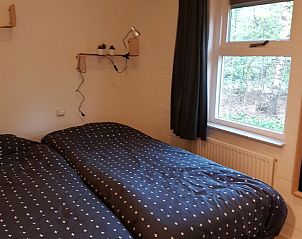 Sfeervolle slaapkamer in Bospark De Schaapskooi vakantiehuis in Epe, Veluwe, met uitzicht op de omliggende natuur.