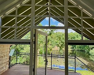 Panoramisch uitzicht vanuit het Vakantiehuisje in Hattem, met een balkon dat uitkijkt op de natuur van Veluwe.