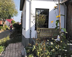 Charmante tuin bij Vakantiehuisje in Houwerzijl, Noordwest Groningen met bloemen en wandelpad.