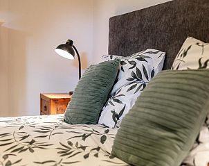 Detail van bed in Verzicht vakantiehuis, Heeswijk-Dinther, met stijlvolle kussens en lamp.