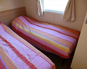 Gezellige slaapkamer in Chalet vakantiehuis Wilbertoord, Noordoost Brabant. Comfortabele bedden met kleurrijk beddengoed voor een ontspannen verblijf.