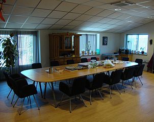 Ruime vergaderruimte in De Lindenhoeve, vakantiehuis in Nistelrode, Noordoost Brabant, met lange tafel en comfortabele stoelen.