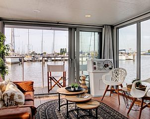 Lichte woonkamer van Vakantiehuis in Dinteloord met uitzicht op het water en de boten.